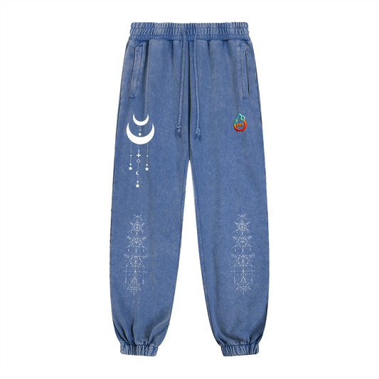 Blue denim jogger pants with white moon and star design on a white background